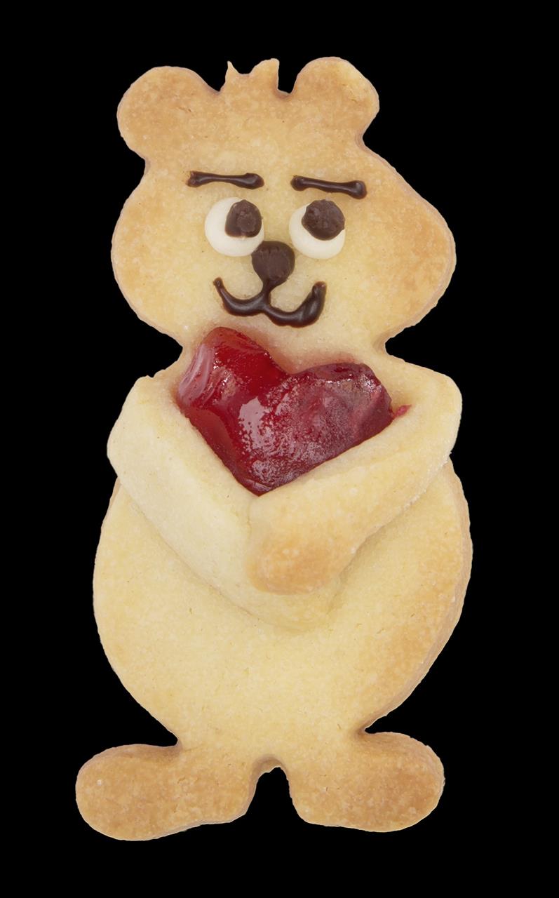 Das Bild zeigt einen Keks in der Form eines Bären. Der Bär hält ein rotes Herz und hat ein Gesicht aus Schokolade und Zuckerguss.
