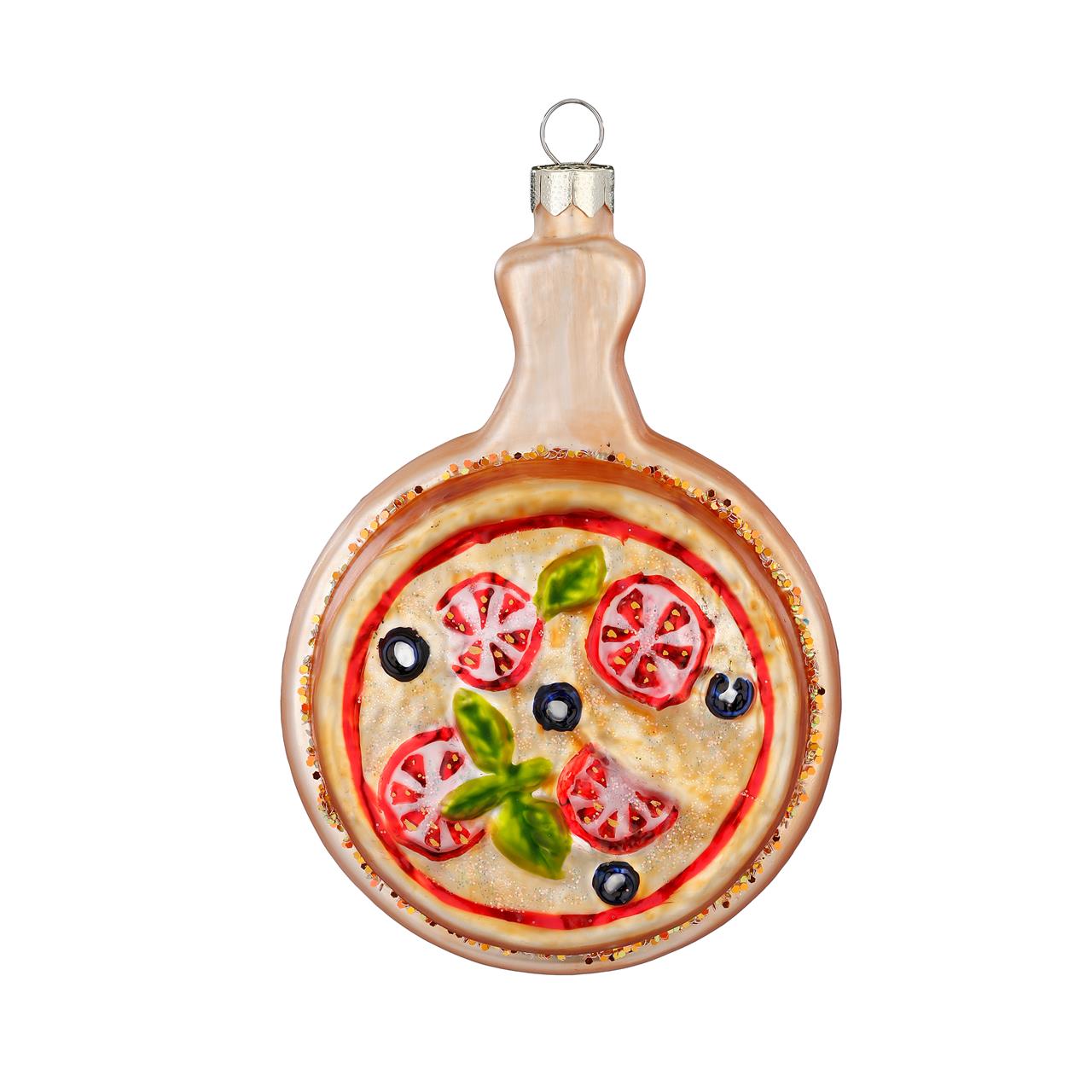 Das Bild zeigt einen Baumanhänger aus Glas in Form einer Pizza auf einem Teller. Die Pizza ist bunt verziert mit Tomaten, Oliven und Basilikum.