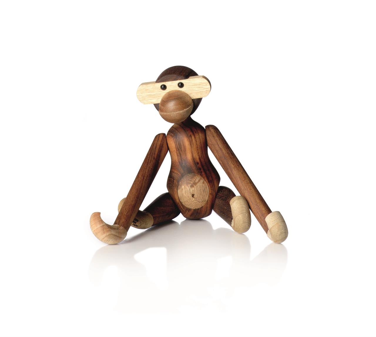 Das Bild zeigt eine kleine Affenfigur aus Holz in einer sitzenden Position. Sie besteht aus Teak- und Limbaholz und hat bewegliche Arme und Beine.