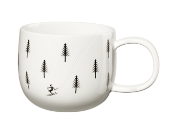 Die Tasse ist weiß und mit schwarzen Tannenbäumen verziert. Auf der Tasse ist außerdem eine kleine Figur beim Skifahren abgebildet.