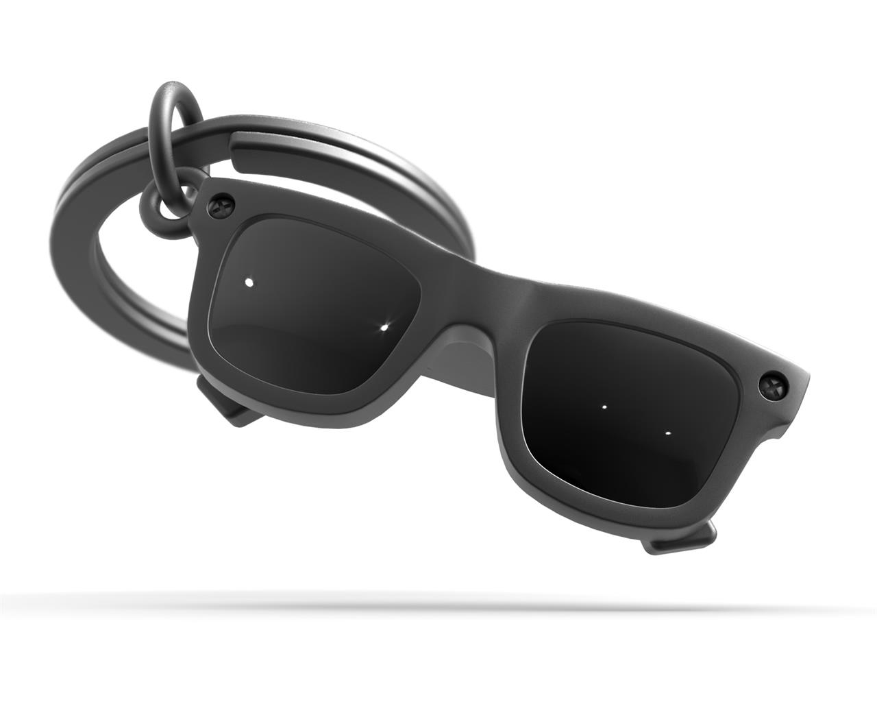 Der Schlüsselanhänger zeigt eine kleine Sonnenbrille als Anhänger. Das Design ist modern und die Farben sind schwarz und silber.