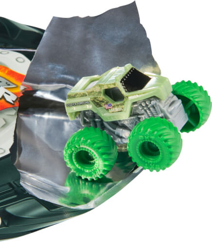 Auf dem Bild ist ein kleines Spielzeug-Monstertruck mit grünen Reifen zu sehen. Es fährt über eine silberne Fläche oder Verpackung.