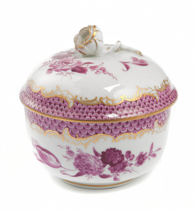 Die Zuckerdose ist aus Porzellan und mit purpurfarbenen Blumenmustern sowie goldenen Verzierungen dekoriert. Sie hat einen Deckel mit einer kleinen, kunstvoll gestalteten Blume als Griff.