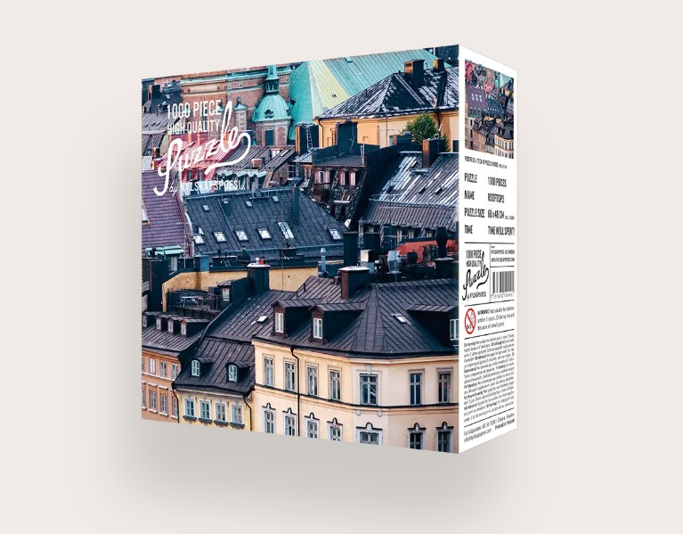 Das Bild zeigt das Produkt 'Puzzle Rooftops 1000 Teile'. Es ist ein 1000-teiliges Puzzle mit einem Bild von Hausdächern.
