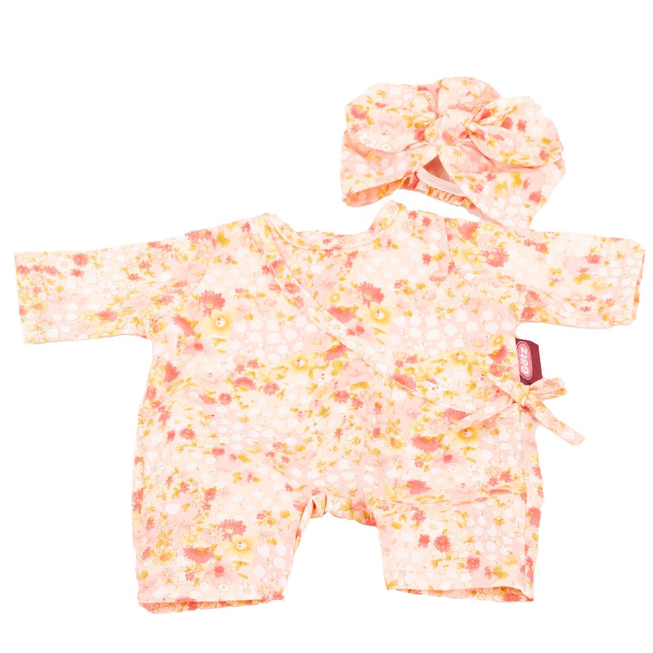 Das Bild zeigt einen Babystrampler mit Blumenmuster in rosa, gelb und orange. Dazu gehört eine passende Mütze mit einer Schleife.