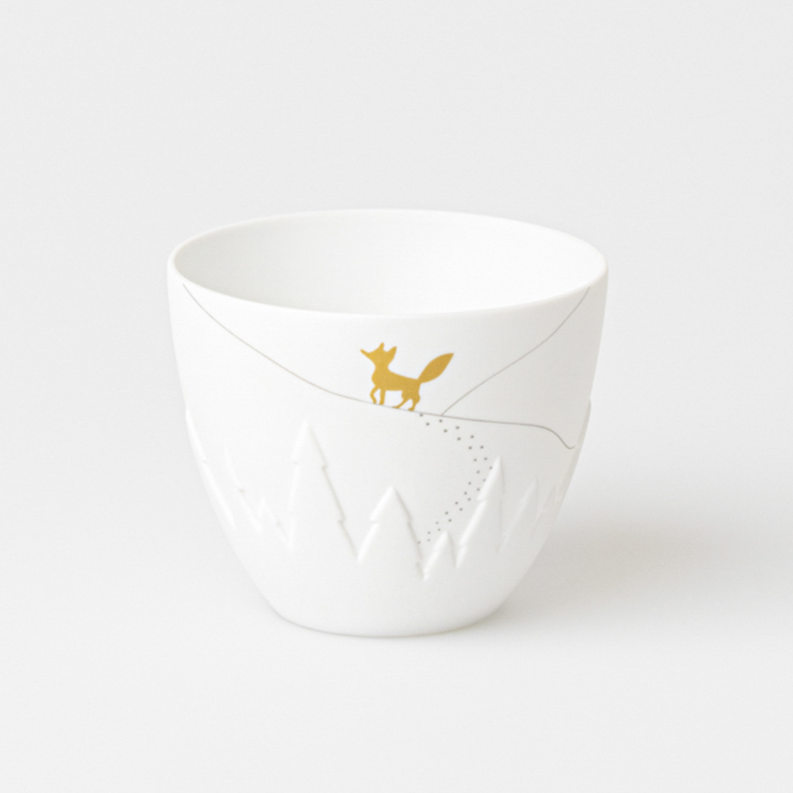 Das Bild zeigt ein kleines, weißes Windlicht mit einem goldenen Fuchs-Motiv. Auf dem Windlicht sind zudem leicht erhabene Tannenbäume und feine Linien zu sehen.