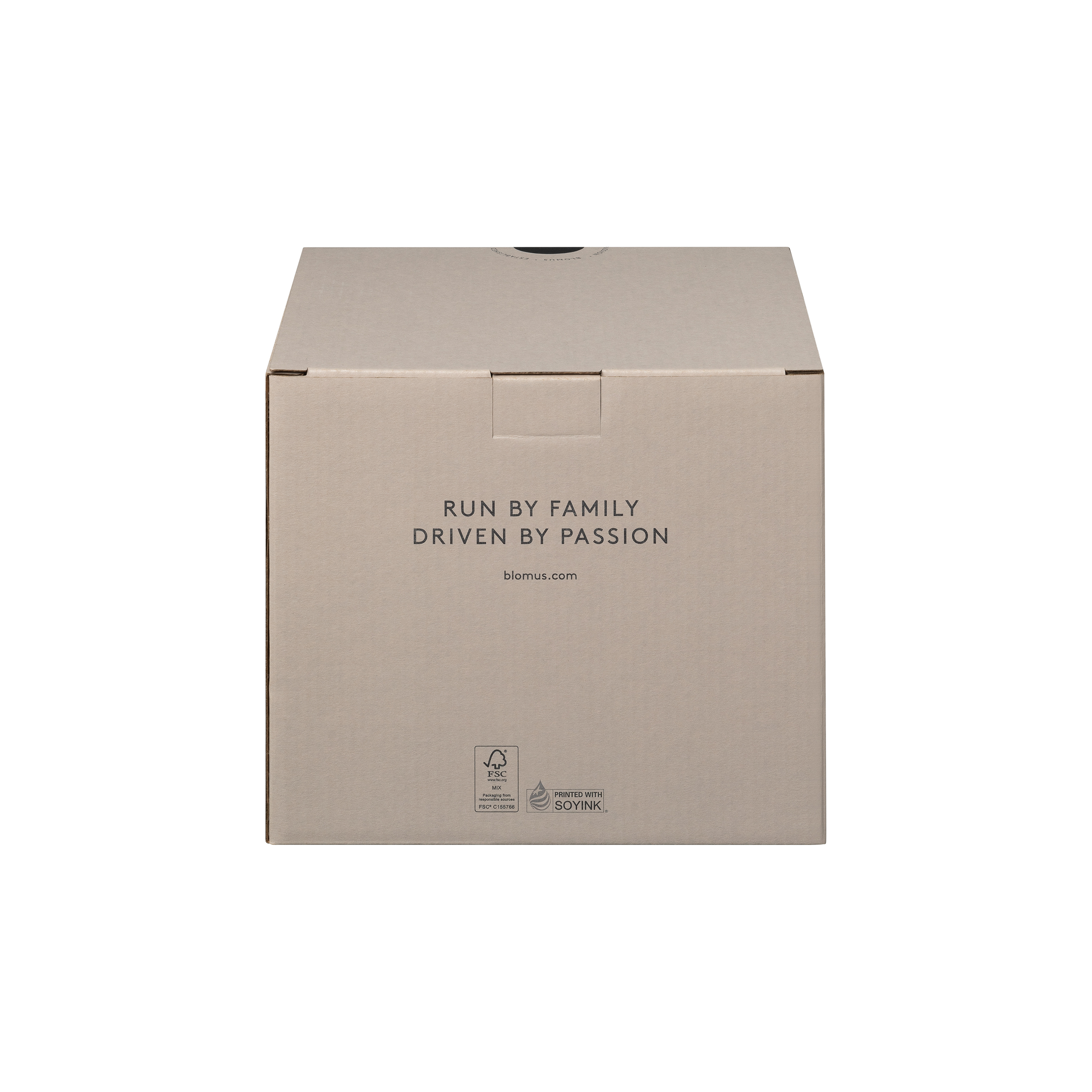 Dies ist ein brauner Karton mit der Aufschrift "RUN BY FAMILY DRIVEN BY PASSION" auf der Vorderseite. Unten befinden sich zusätzliche Symbole und die Webseite blomus.com.