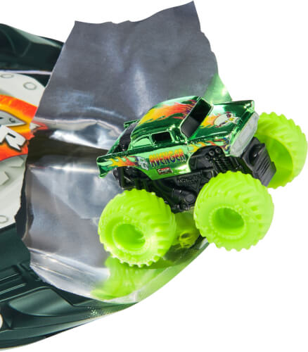Ein kleines grünes Spielzeug-Monstertruck-Auto mit leuchtend gelben Reifen fährt über eine silberne Rampe. Das Auto hat das Wort "Avenger" auf der Seite stehen.