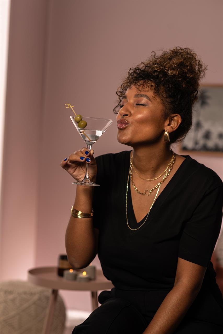 Eine Frau hält ein Martini-Glas mit zwei Oliven und lächelt mit geschlossenen Augen. Das Bild zeigt das Produkt "4er Martini Bar Special 86".