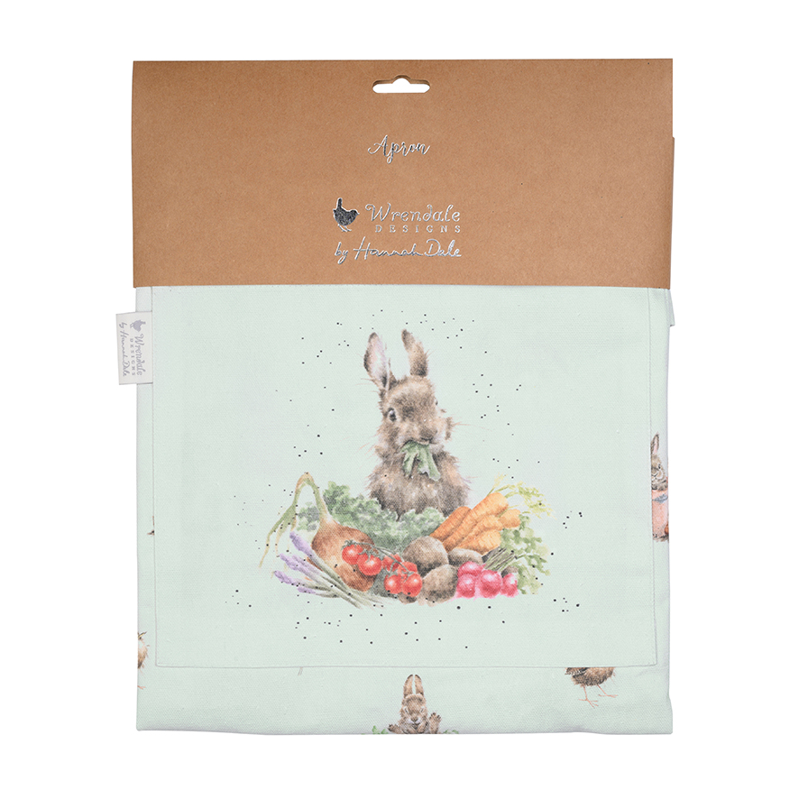 Auf der Schürze ist ein Hase abgebildet, der von frischem Gemüse umgeben ist. Die Verpackung zeigt das Design „Gartenfreunde Hase“ von Wrendale Designs by Hannah Dale.