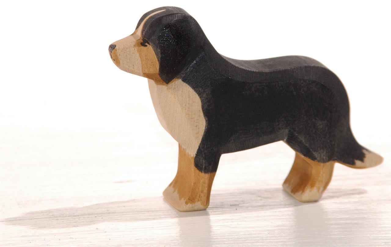 Das Bild zeigt eine Holzfigur eines Berner Sennenhundes. Die Figur ist in Schwarz, Braun und Beige bemalt.