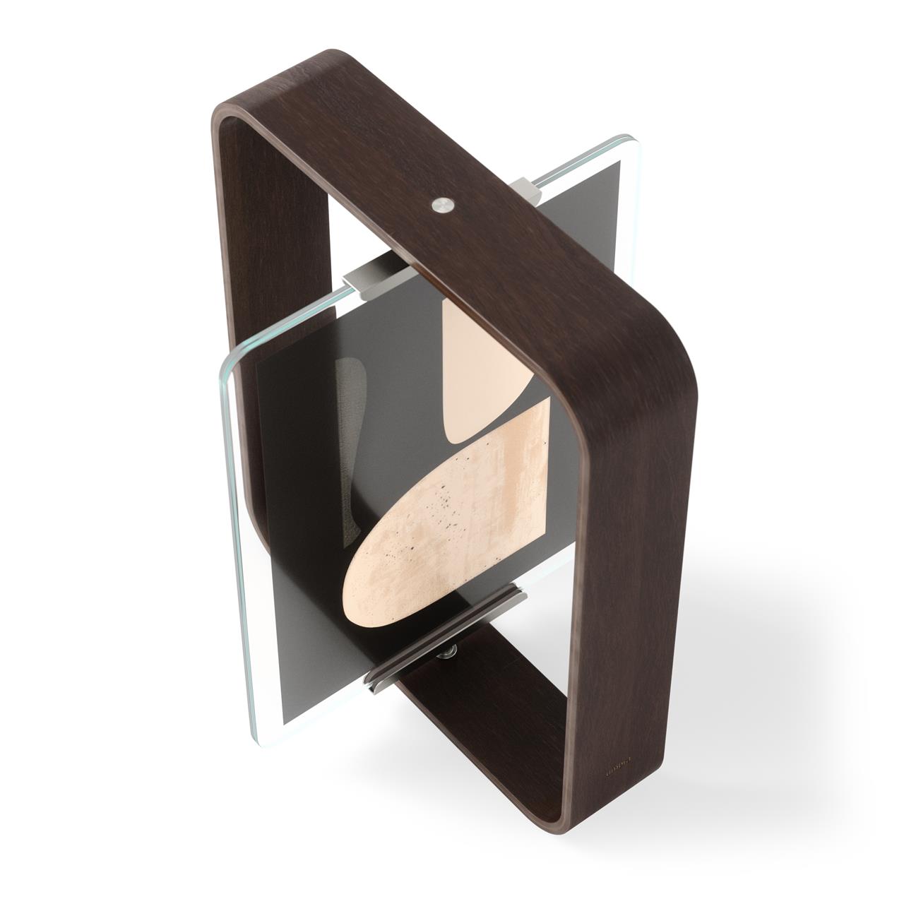 Der BELLWOOD DESK FRAME 20x25 AGED WALNUT ist ein moderner Tischbilderrahmen mit gebogenem Rahmen aus dunklem Walnussholz. Er hält ein Foto oder Bild zwischen zwei Glasscheiben und steht stabil auf dem Schreibtisch.