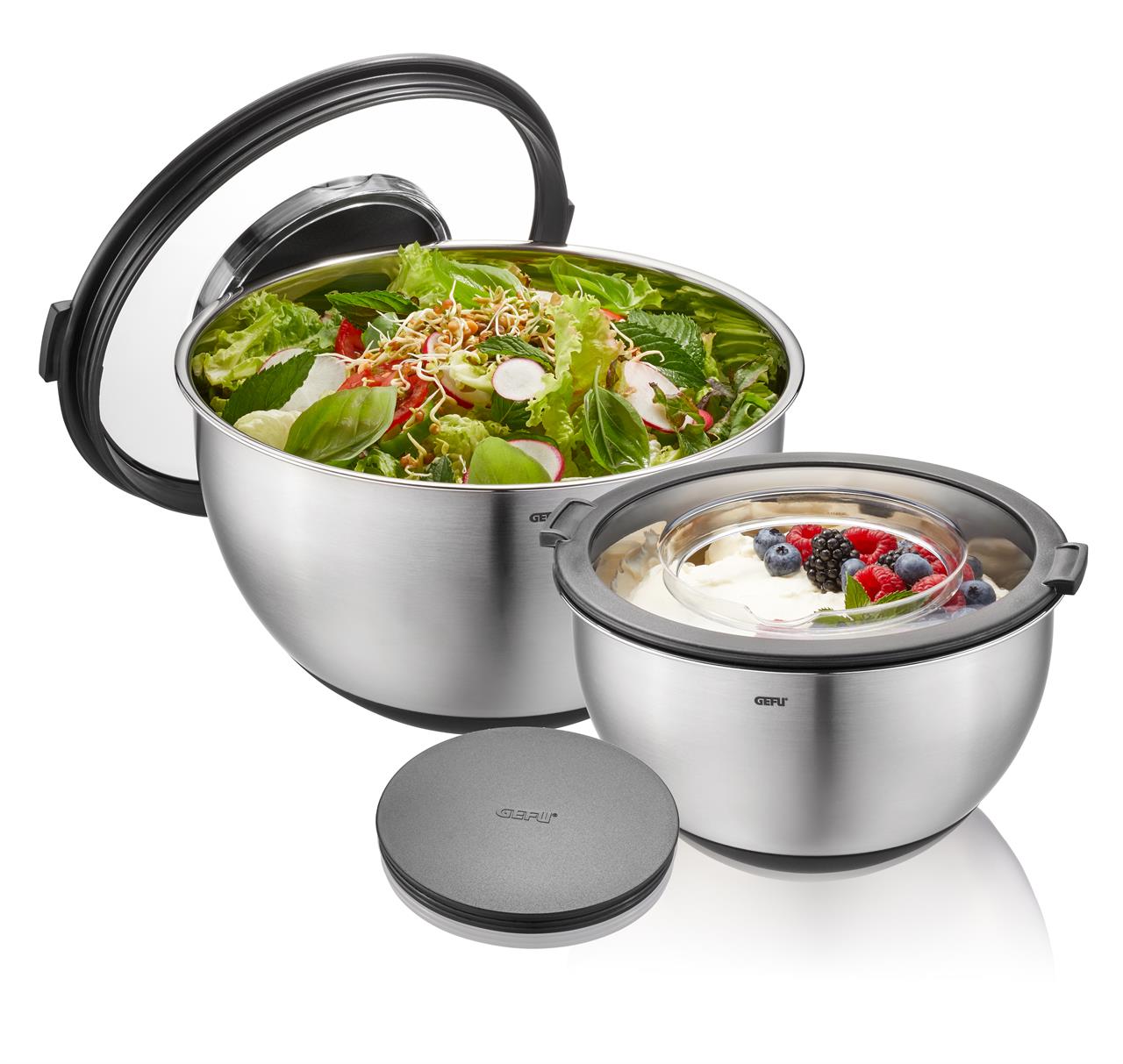 Das Bild zeigt ein Schüssel-Set mit Spritzschutzdeckel der Marke MUOVO, bestehend aus zwei Schüsseln. In den Schüsseln befinden sich ein frischer Salat und ein Dessert mit Beeren.