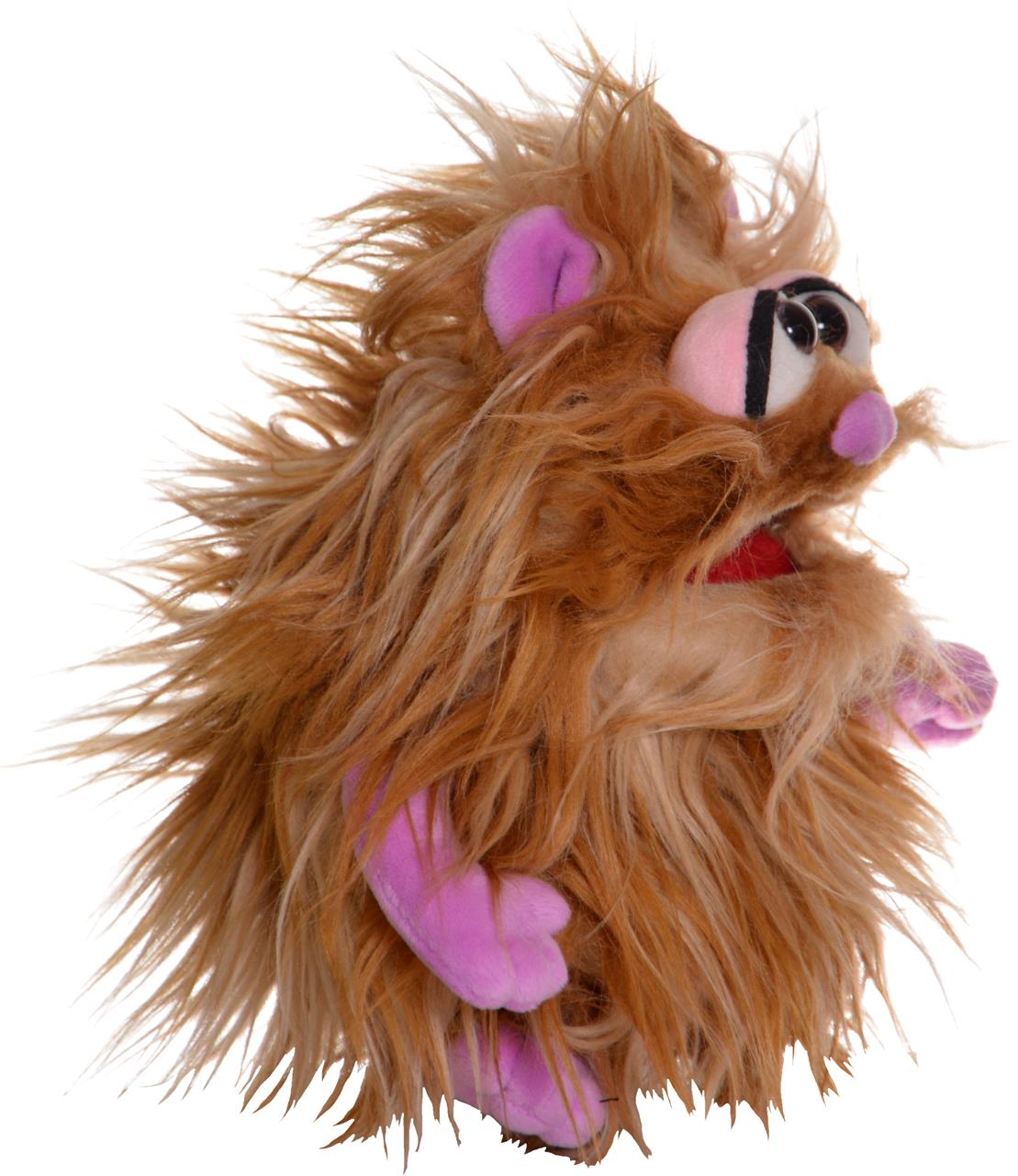 Das Bild zeigt eine Handpuppe mit beigem, zotteligem Fell. Die Puppe hat lila Hände, Ohren und eine auffällige Nase.
