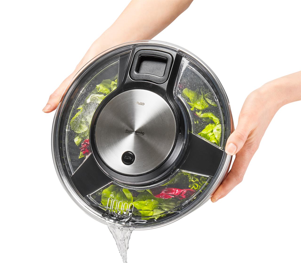 Auf dem Bild ist eine Salatschleuder SPEEDWING® aus Edelstahl zu sehen, in der frischer Salat gewaschen wird. Wasser wird durch eine integrierte Öffnung im Deckel abgegossen.