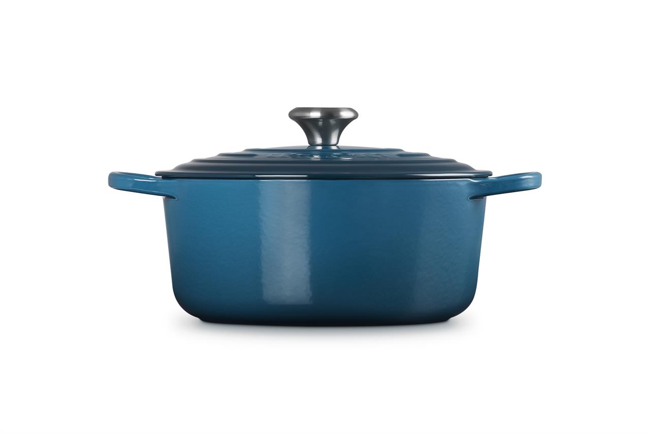 Auf dem Bild ist ein runder Bräter in der Farbe Deep Teal mit einem Durchmesser von 26 cm zu sehen. Der Bräter hat zwei Griffe und einen Deckel mit einem silbernen Knauf.