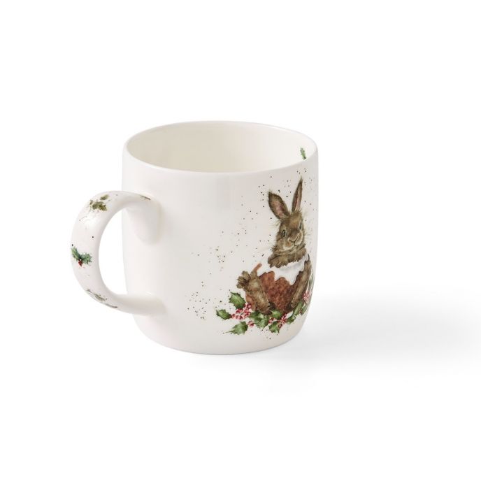 Auf der Tasse ist ein Hase mit weihnachtlichen Dekorationen abgebildet. Die Tasse ist weiß und hat auch ein kleines Weihnachtsmotiv am Henkel.