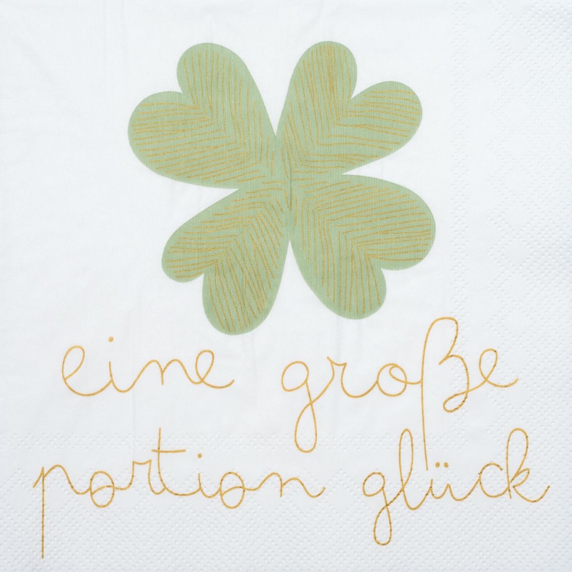 Die Serviette zeigt ein großes, grünes Kleeblatt in der Mitte. Darunter steht in gelber Schrift: "eine große Portion Glück".