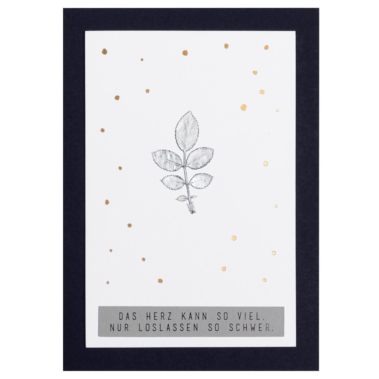 Die Karte zeigt eine einfache Zeichnung eines Zweigs mit Blättern in der Mitte, umgeben von goldenen Punkten. Unten steht der Text: „Das Herz kann so viel. Nur loslassen so schwer.“