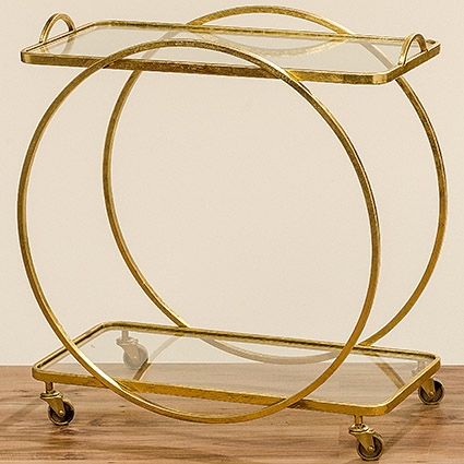 Der Tisch "Ohio H.75cm Eisen" ist ein eleganter Servierwagen mit einem goldenen Metallrahmen und zwei Glasablagen. Er steht auf vier Rollen und hat ein modernes, rundes Design.