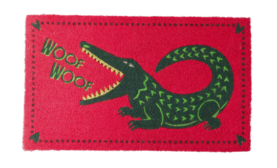 Auf dem Bild ist eine Fussmatte mit dem Motiv 'Woof Woof Krokodil' in Neon Pink zu sehen. Das verspielte Design sorgt für gute Laune im Eingangsbereich.