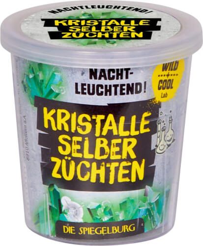 Auf dem Bild ist ein Behälter mit der Aufschrift „Kristalle selber züchten“ zu sehen. Das Produkt leuchtet im Dunkeln und ist von der Marke „Die Spiegelburg“.