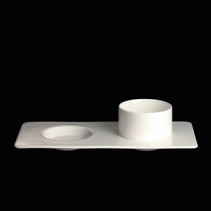 Das Bild zeigt ein rechteckiges Tablett aus weißem Fine Bone China mit zwei Vertiefungen. Auf dem Tablett steht ein passender runder Becher.