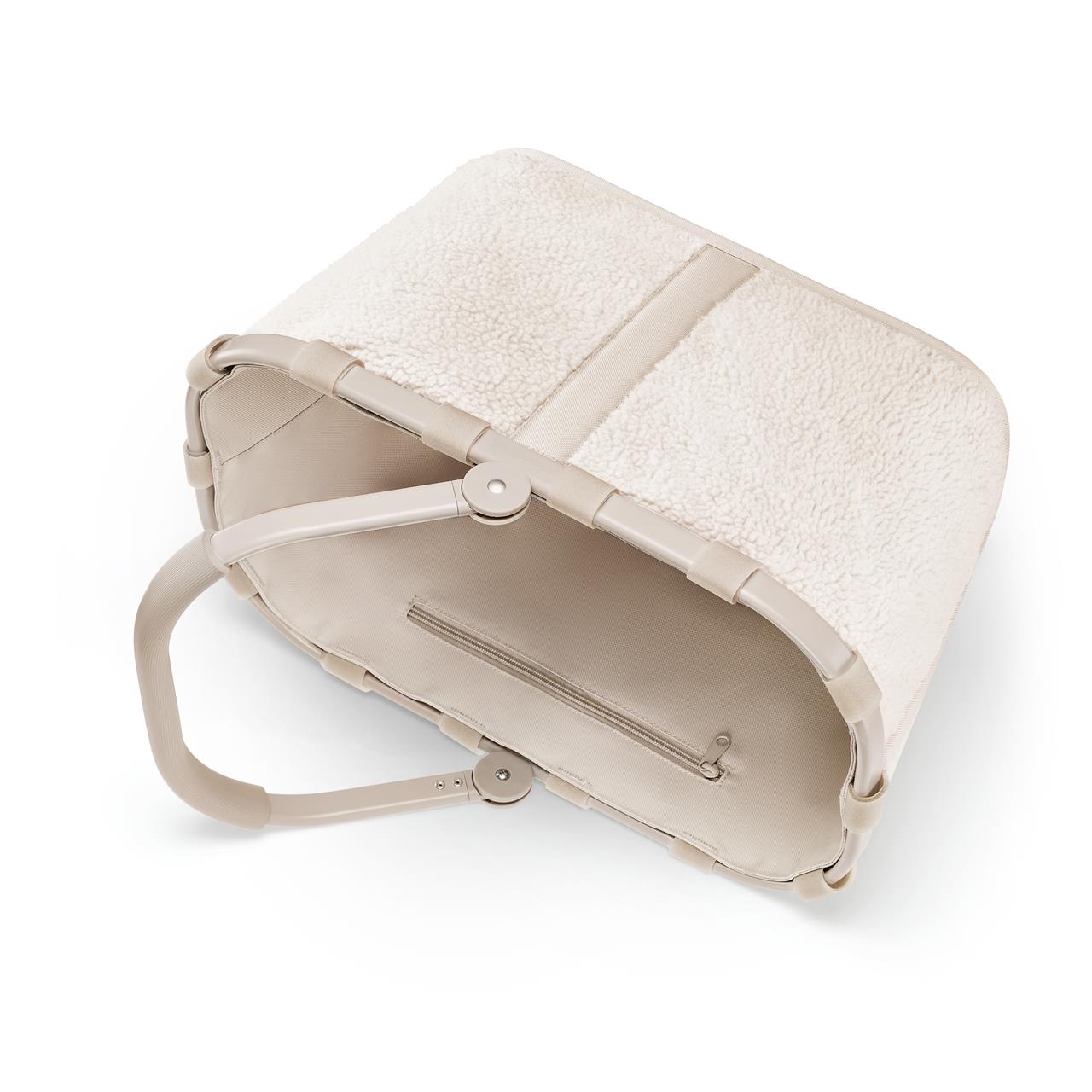 Der Carrybag teddy sand Einkaufskorb ist beige und hat eine weiche, flauschige Außenseite. Im Inneren befindet sich ein Reißverschlussfach für zusätzlichen Stauraum.