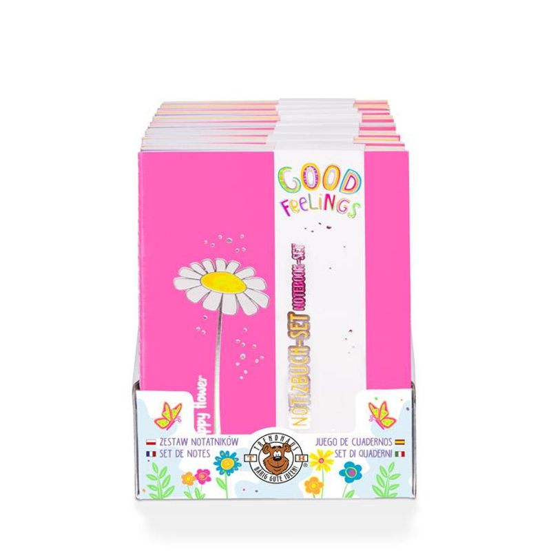 Das Bild zeigt ein Set von Notizheften mit pinkem Cover und einer Blume darauf. Auf dem Cover steht "GOOD FEELINGS" und das Set enthält drei Hefte mit jeweils 32 karierten Seiten.