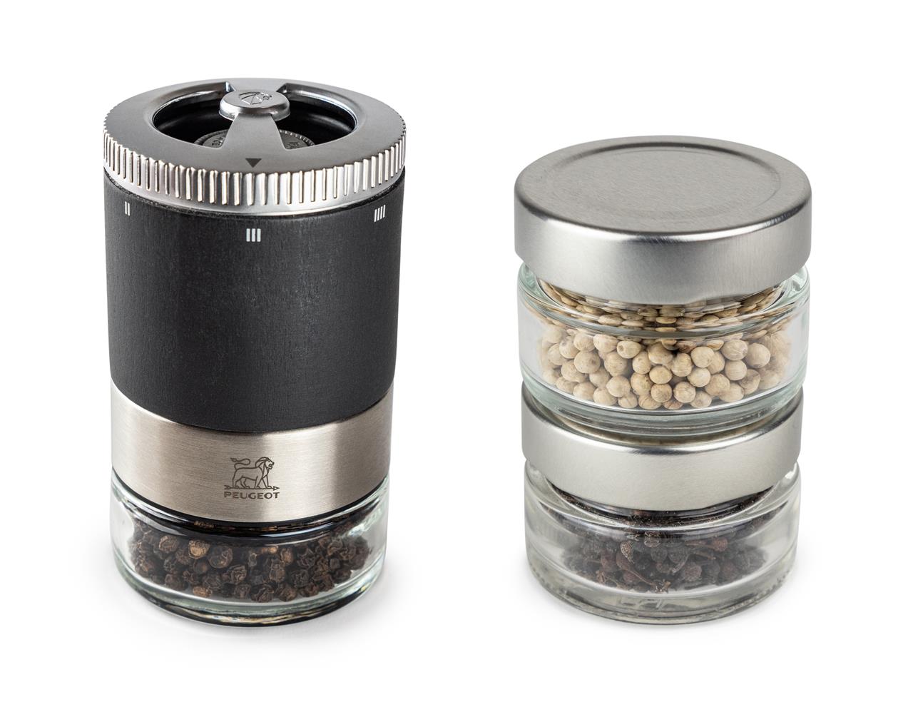 Das Bild zeigt eine Pfeffermühle in modernem Design mit dunklem Gehäuse und Edelstahlelementen. Daneben stehen drei kleine Gläser, die mit unterschiedlichen Pfeffersorten gefüllt sind.