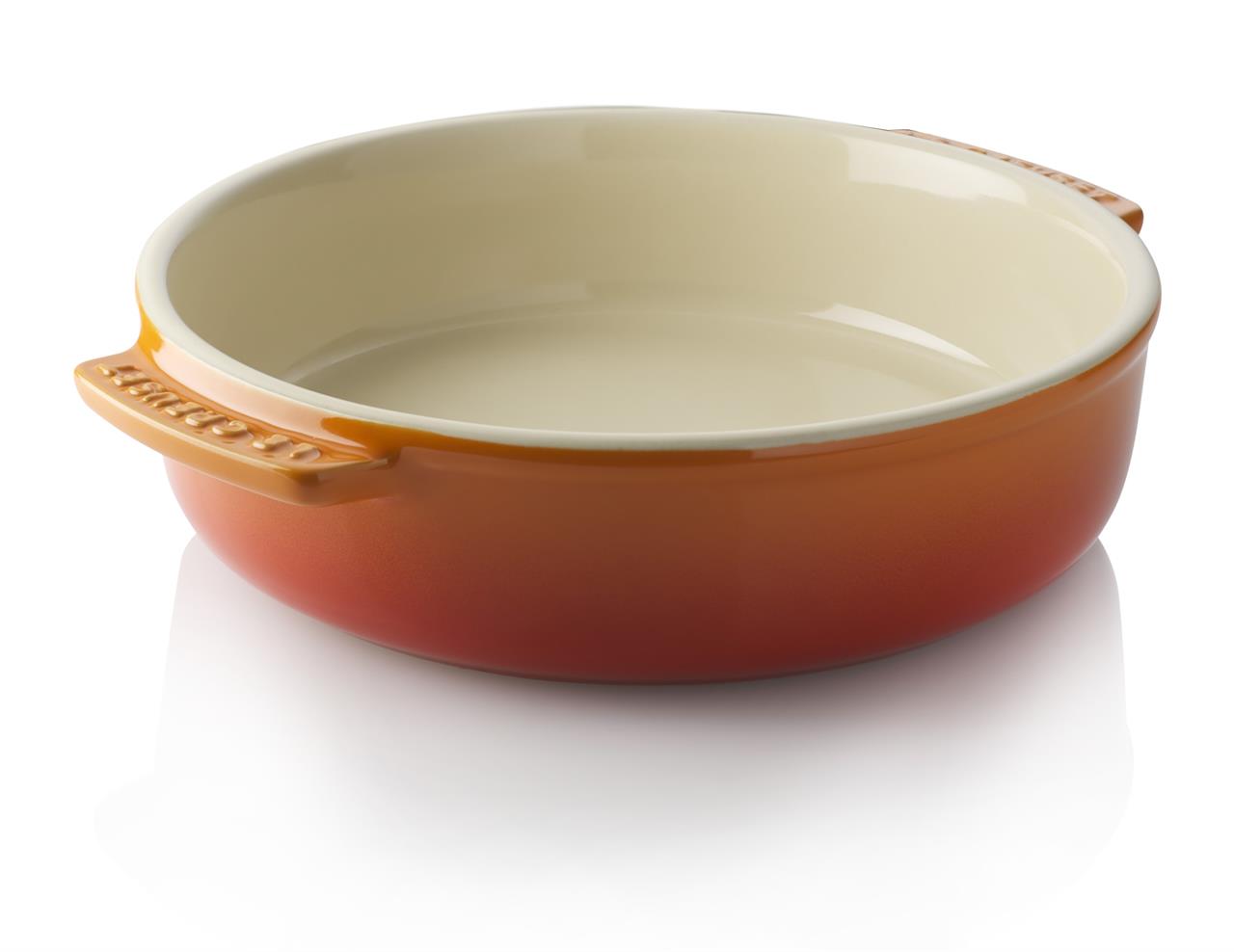 Die Abbildung zeigt eine runde Tapasschale in Ofenrot mit zwei kleinen Griffen. Das Innere der Schale ist hell und die Außenseite ist rot-orangefarben.