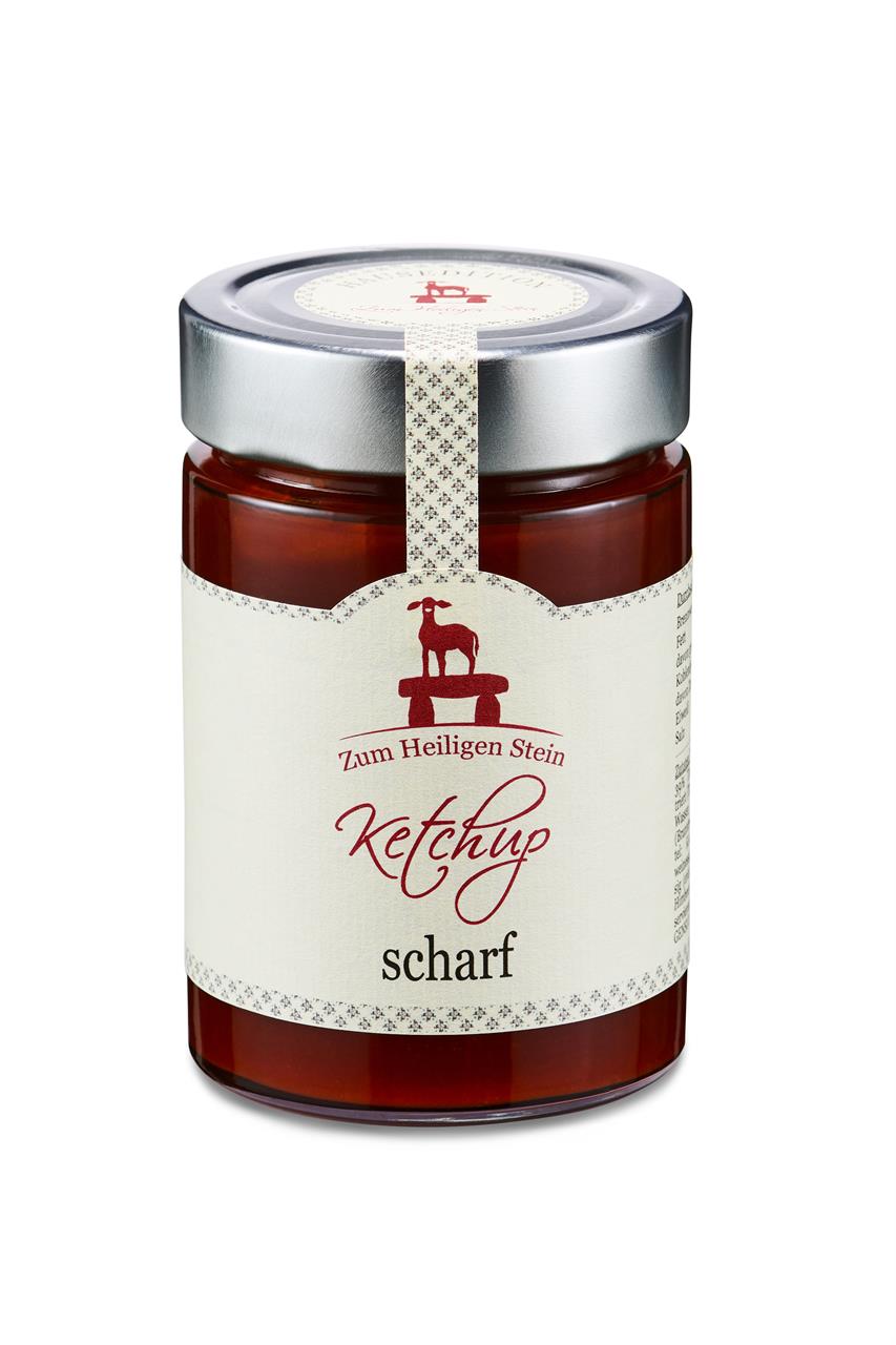 Das Bild zeigt ein Glas scharfes Ketchup mit einem silbernen Deckel. Auf dem Etikett steht "Zum Heiligen Stein Ketchup scharf".
