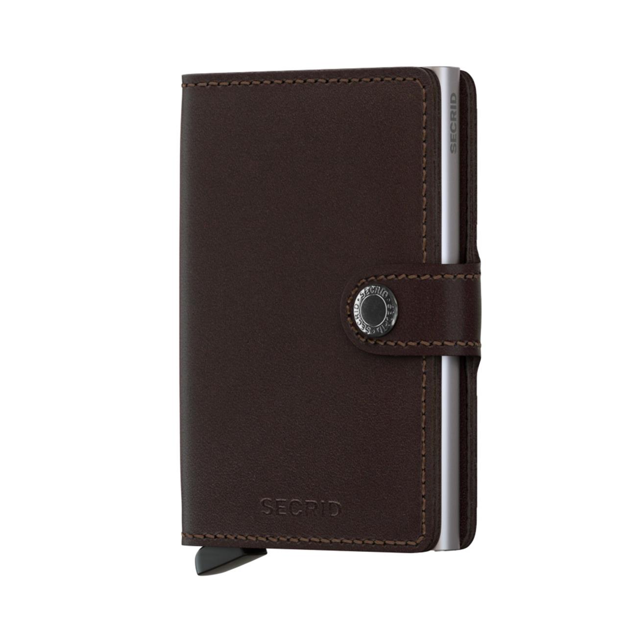 Das Bild zeigt ein dunkelbraunes Miniwallet mit einem Verschlussknopf. Das Portemonnaie besteht aus Leder und hat dezente Nähte sowie einen silbernen Einsatz an der Seite.