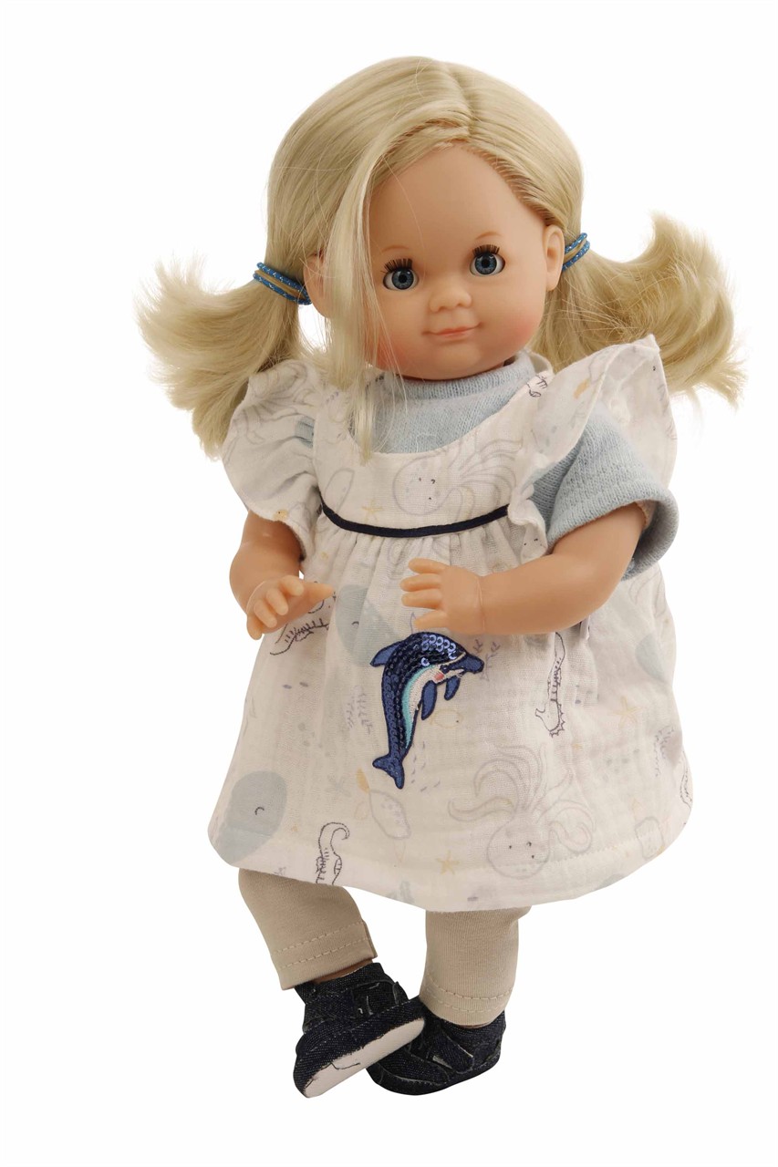 Das Bild zeigt eine Puppe mit blonden Haaren und blauen Schlafaugen. Sie trägt ein Kleid mit einem Meerestiermotiv und hat blaue Haargummis.