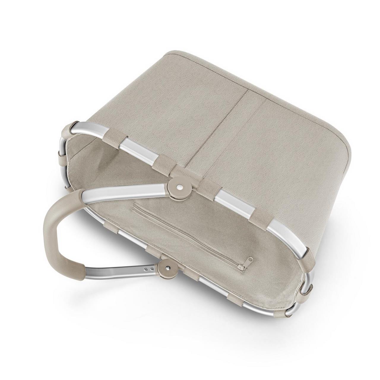 Der Einkaufskorb "Carrybag Herringbone Sand" ist in einem hellen Beigeton gehalten. Er verfügt über einen stabilen Aluminiumrahmen und einen bequemen Tragegriff.
