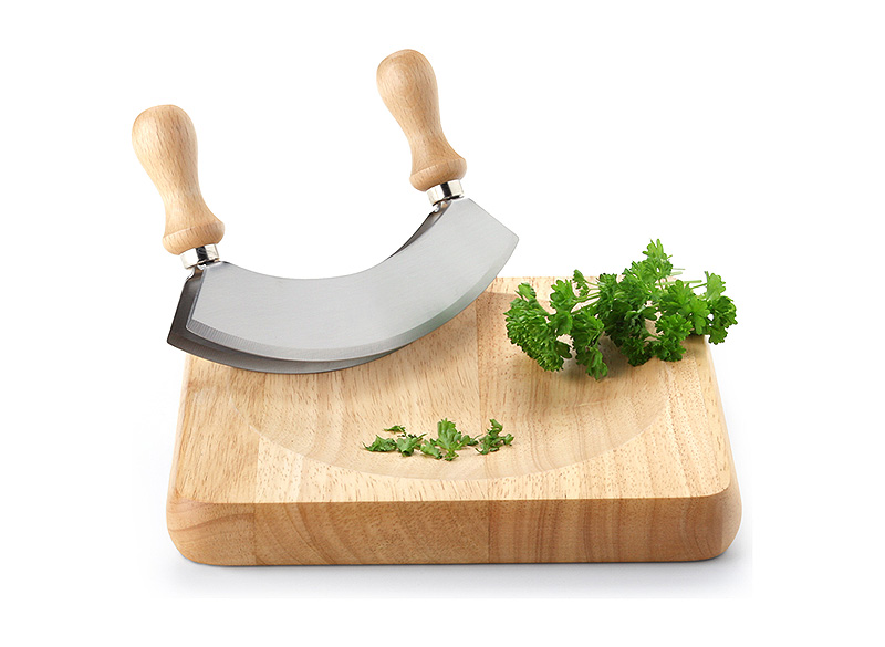 Das Bild zeigt ein Wiegemesser mit Holzgriffen und ein passendes Schneidebrett aus Gummibaumholz. Auf dem Brett liegt frische, gehackte Petersilie.
