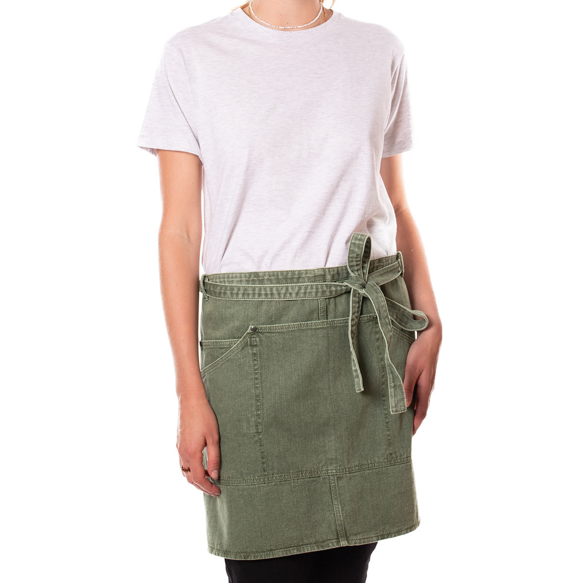 Die Schürze P'tit in der Farbe Vert Olive ist auf dem Bild zu sehen. Sie bietet Schutz beim Kochen oder Backen.