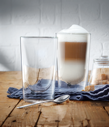 Das Bild zeigt zwei doppelwandige Gläser des Produkts „Latte Macchiato 2tlg. Kineo“. Eines der Gläser ist mit Latte Macchiato gefüllt, das andere ist leer.