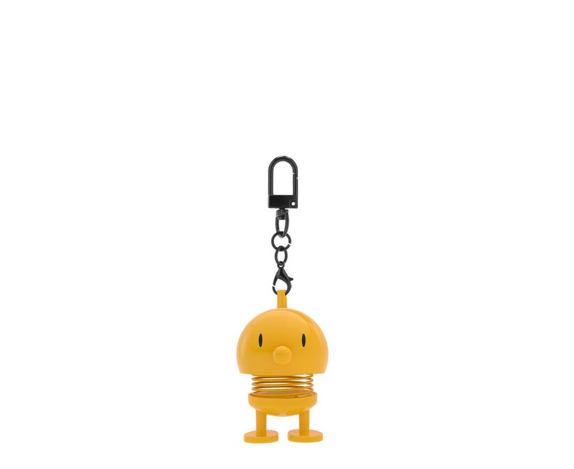 Auf dem Bild ist der Hoptimist Bag Charm in Gelb zu sehen. Dieser Taschenanhänger ist auffällig und fröhlich.