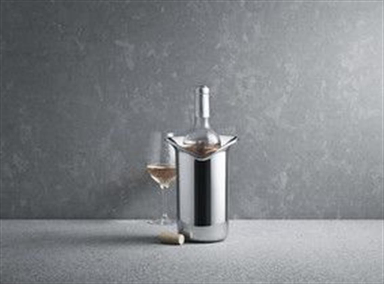 Auf dem Bild ist ein Edelstahl-Weinkühler mit einer Weinflasche darin zu sehen. Daneben stehen ein Weinglas mit etwas Wein und ein Flaschenkorken auf dem Tisch.