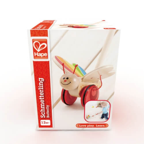 Auf dem Bild ist eine Verpackung eines Hape-Spielzeugs zu sehen, das einen Schmetterling darstellt. Das Spielzeug ist für Kinder ab 12 Monaten geeignet.