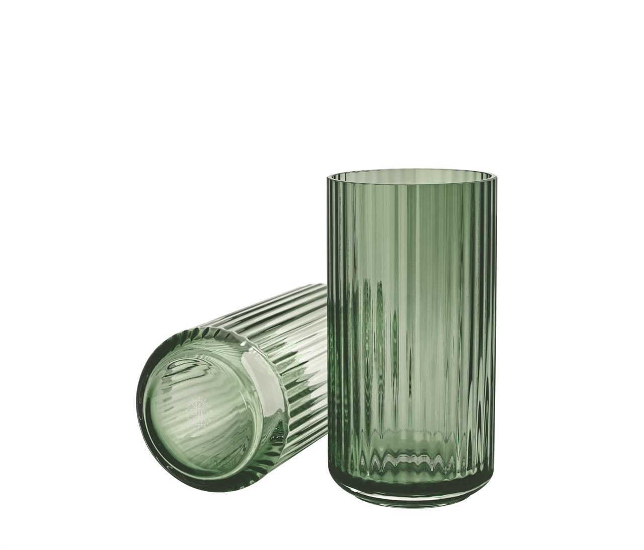 Das Bild zeigt zwei grüne Glasvasen mit Rillenmuster, eine stehend und eine liegend. Die Vasen sind 20 cm hoch und tragen den Namen "Lyngby Vase".