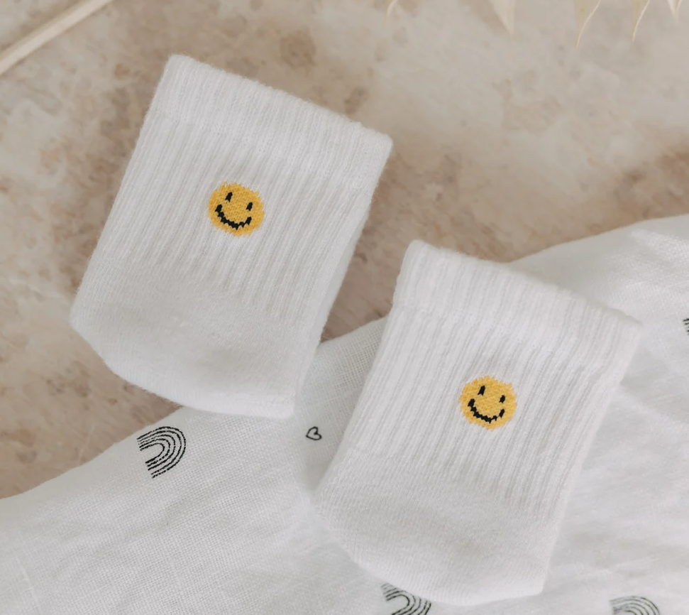 Auf dem Bild sieht man Babysocken mit einem Smiley-Motiv in Größe 16-18. Die Socken sind für Babys gedacht.