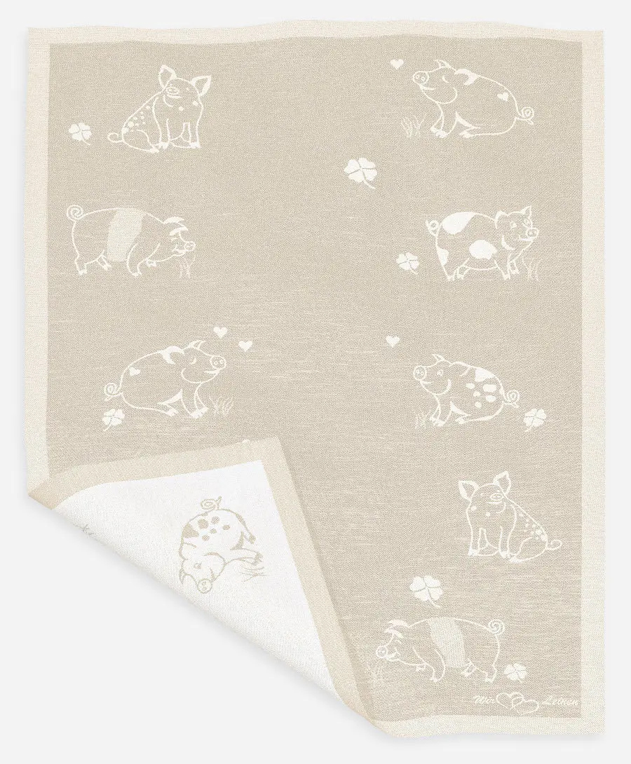 Das Bild zeigt ein naturfarbenes Halbleinen-Geschirrtuch mit den Maßen 45x73 cm. Auf dem Tuch sind mehrere süße Schweinchen und Kleeblätter als Muster abgebildet.