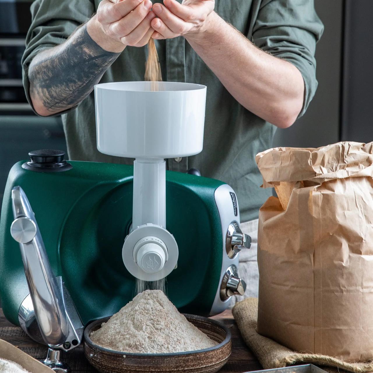 Eine Person benutzt eine Getreide- und Kaffeemühle, um frisches Mehl zu mahlen. Das gemahlene Mehl fällt in eine Schüssel unter der Mühle.
