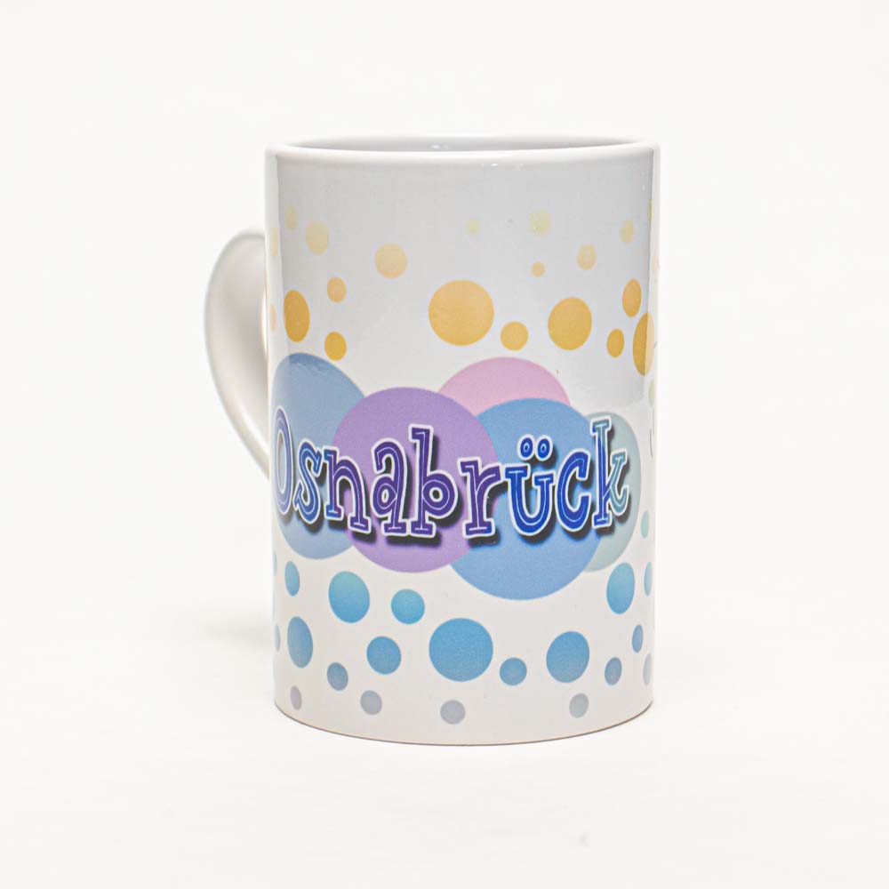 Die Abbildung zeigt eine weiße Tasse mit bunten Kreisen in Blau, Lila und Gelb. Auf der Tasse steht das Wort "Osnabrück" in verspielter Schrift.