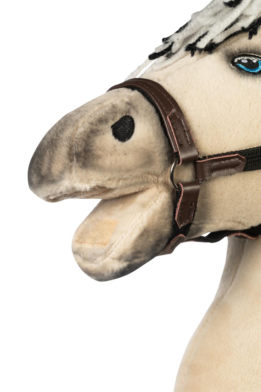 Das Bild zeigt den Kopf eines Hobby Horses mit hellbraunem Stoff und einer schwarzen Trense. Die Mähne besteht aus weißen und schwarzen Fäden, und das Pferd hat ein auffälliges blaues Auge.