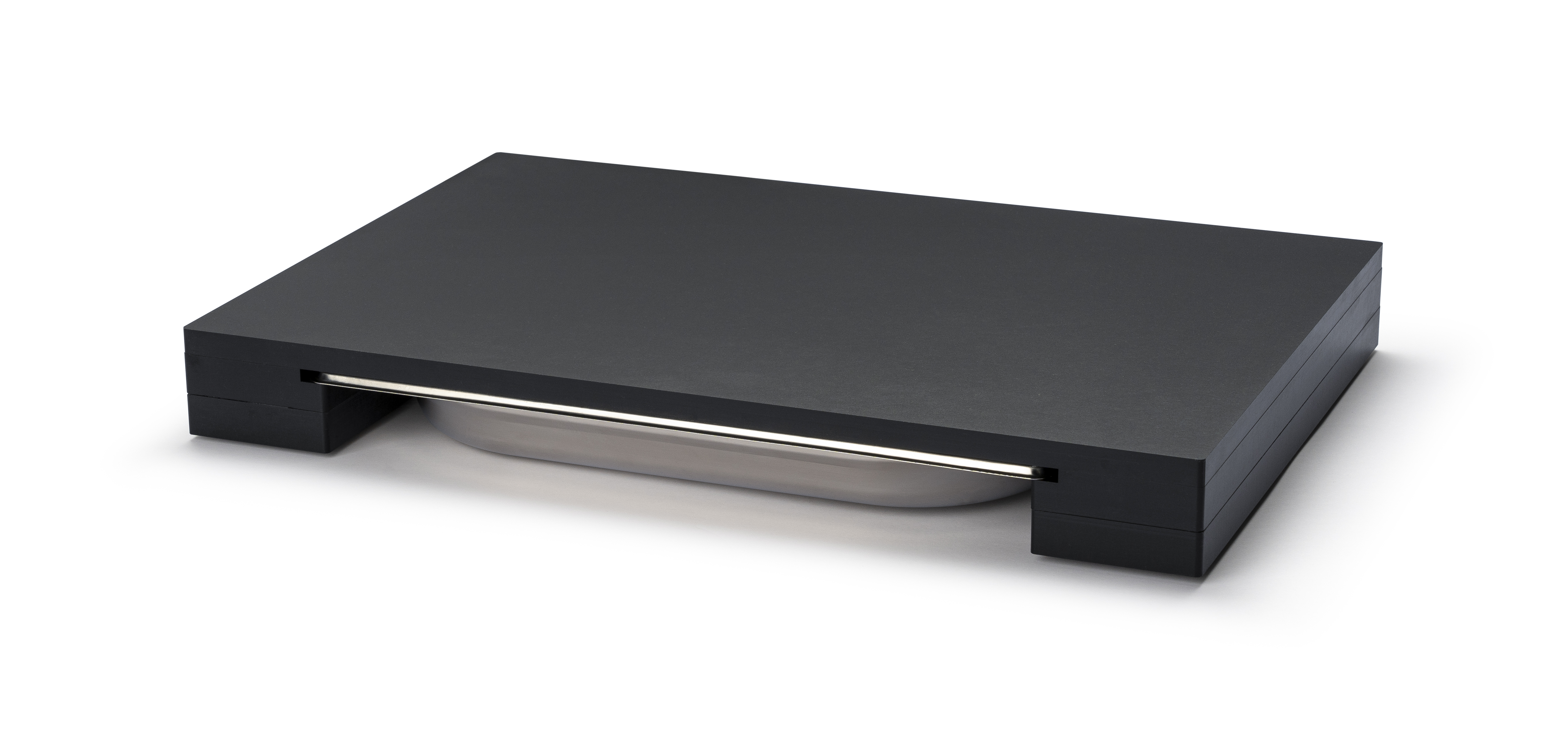 Das Bild zeigt einen rechteckigen schwarzen Gegenstand mit einer flachen Oberfläche. Unter der Oberfläche ist eine silberne Schale teilweise sichtbar.