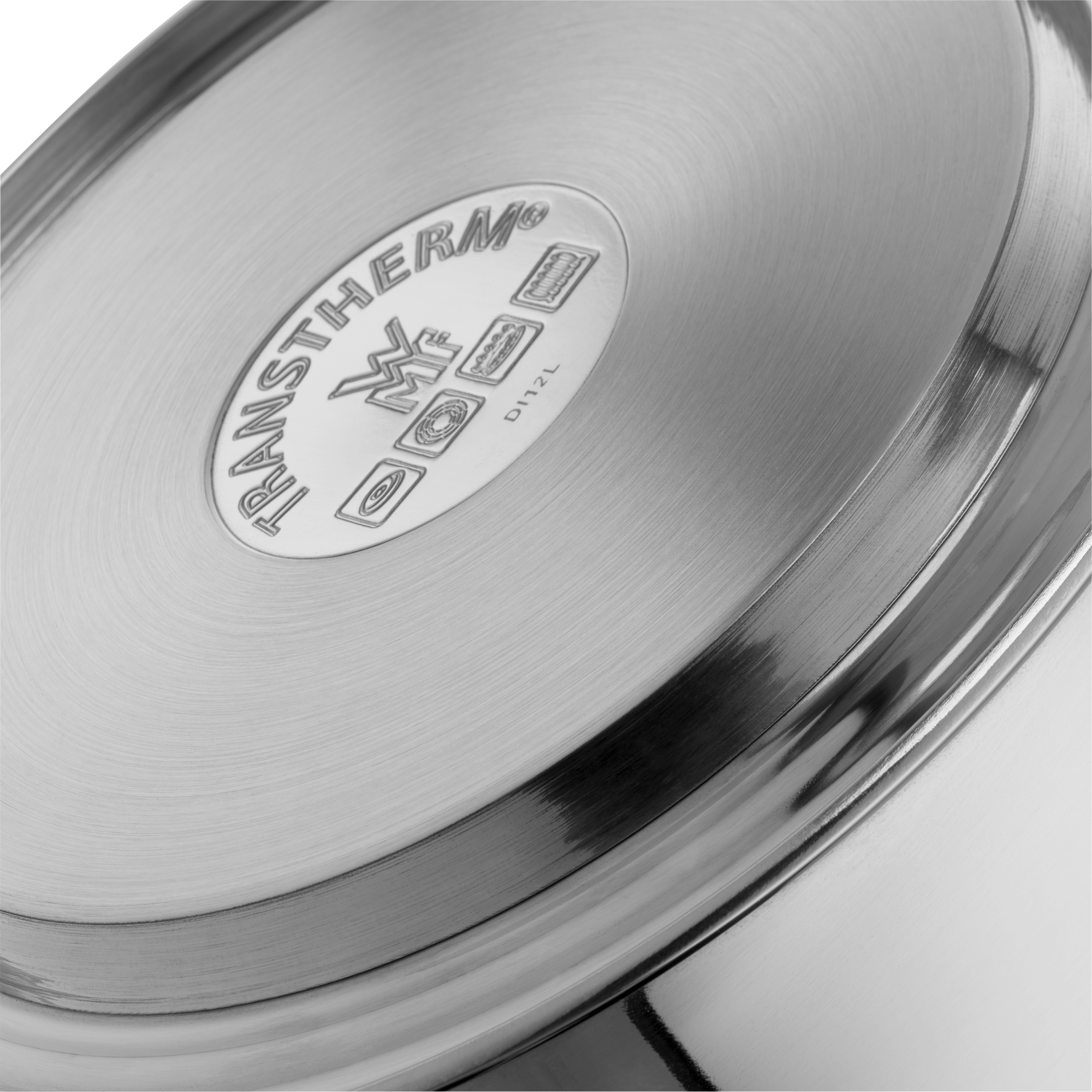 Das Bild zeigt den Boden eines Edelstahltopfes mit der Gravur "TransTherm" und mehreren Symbolen. Die Oberfläche ist glänzend und glatt verarbeitet.
