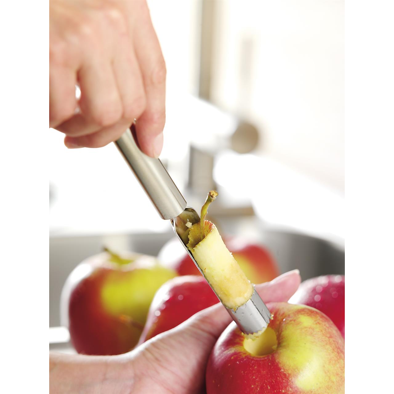 Das Bild zeigt, wie mit dem Apfelausstecher Profi Plus das Kerngehäuse aus einem Apfel entfernt wird. Der Apfelausstecher hält das Kerngehäuse nach dem Ausstechen fest.